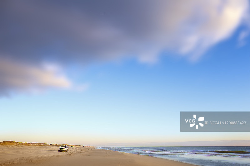 令人惊叹的柔软的蓝色天空，蓬松的云和渔民在岛海滩州立公园图片素材
