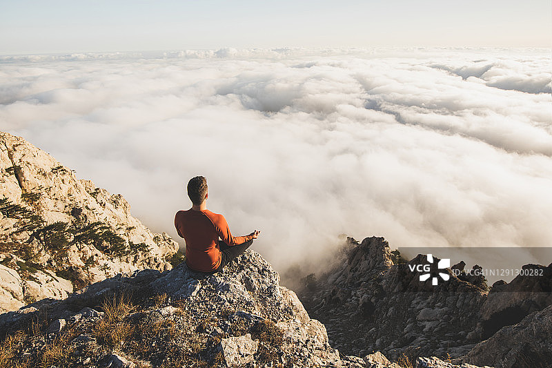 一个人在山上独自练习瑜伽，可以看到很低的云图片素材