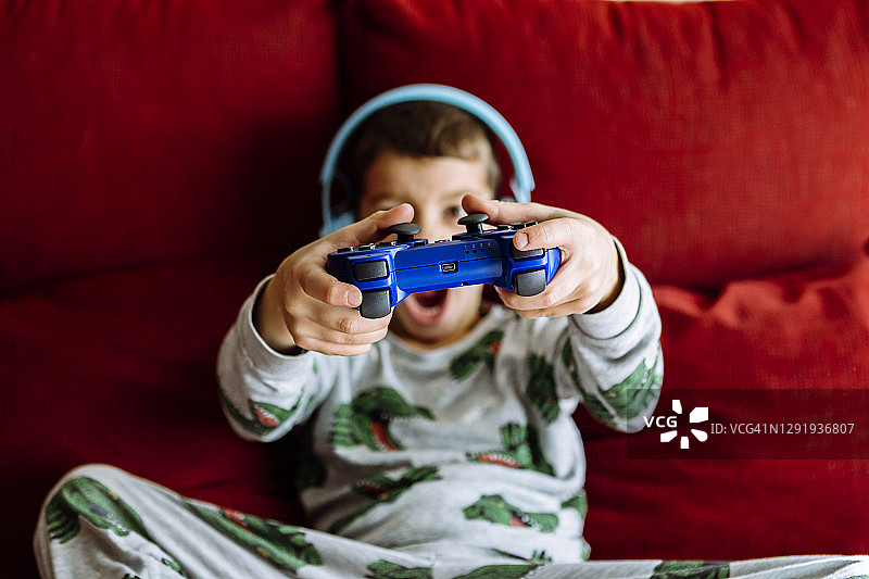 男孩戴着耳机在家里的沙发上看视频游戏图片素材