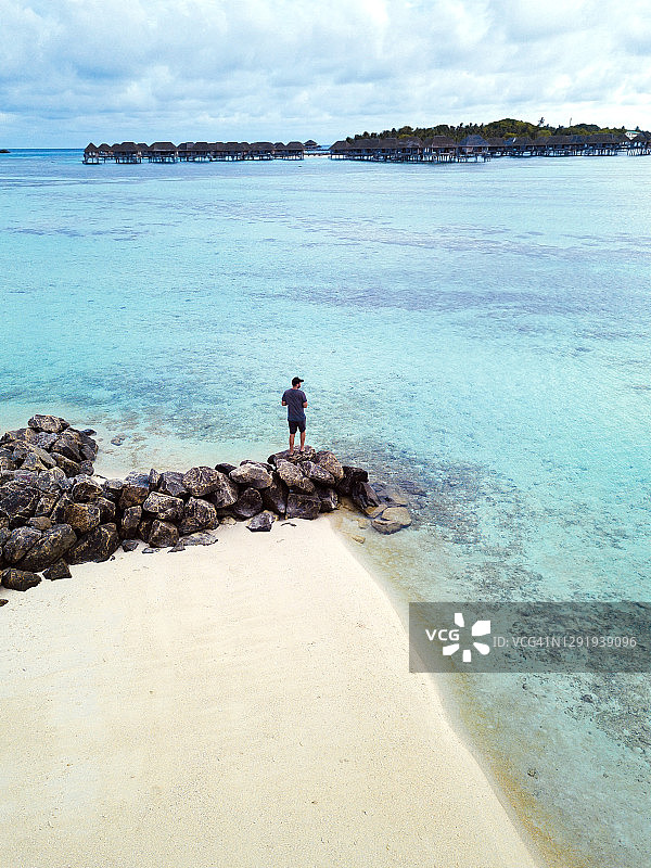 马尔代夫，卡福环礁，鸟瞰图上的人独自站在挡土墙上，胡拉岛的沙滩图片素材
