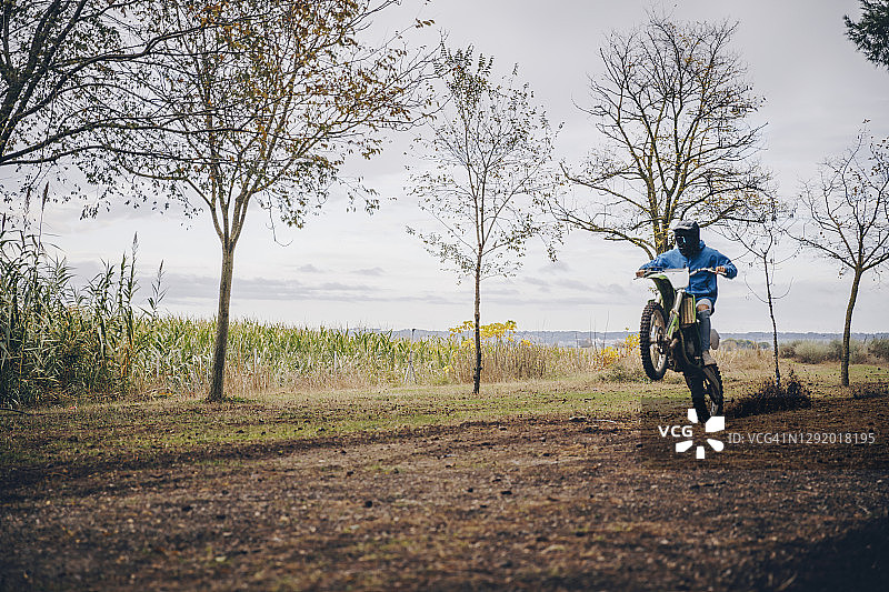 在秋天的森林里，年轻的男性摩托车手表演特技图片素材