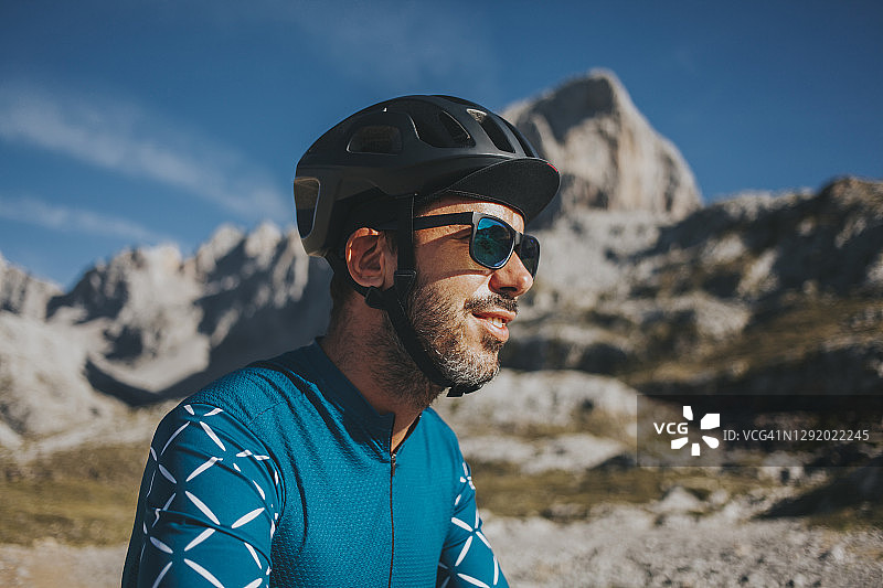阳光明媚的一天，在西班牙坎塔布里亚的欧洲公园，一名骑自行车的人戴着太阳镜和自行车头盔图片素材