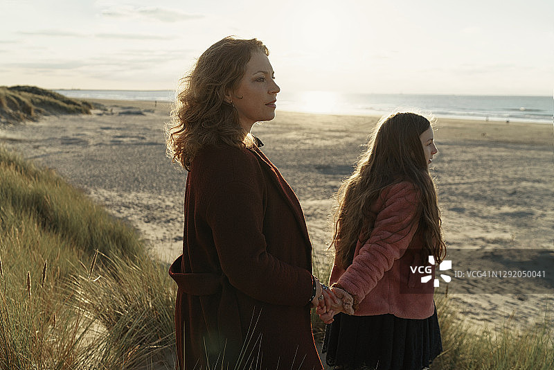 母女站在沙滩上，背对着海景图片素材