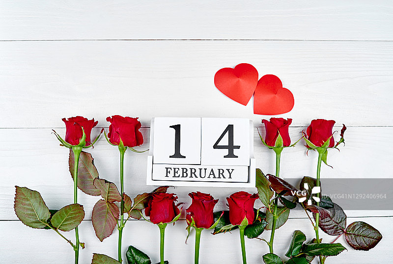 情人节背景以红玫瑰、两颗心和2月14日木版日历，复制空间。贺卡模型。爱的概念。俯视图，平放图片素材