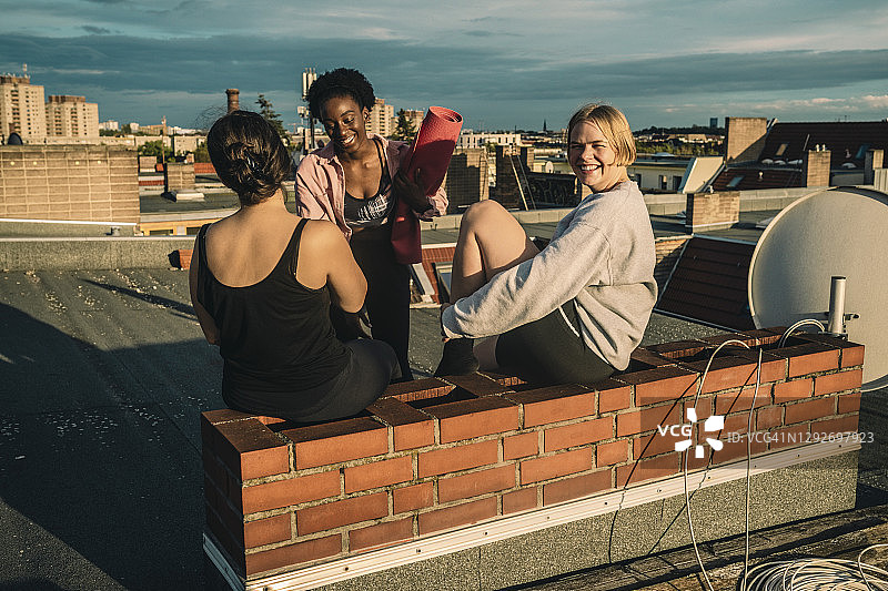 日出时在屋顶上做完瑜伽后微笑的女性朋友的肖像图片素材
