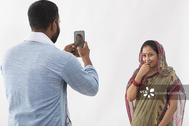 一个农村的丈夫在手机里点击他妻子的照片图片素材