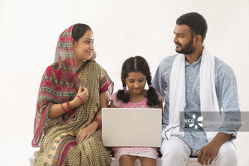 一个农村夫妻和女儿使用笔记本电脑的肖像图片素材