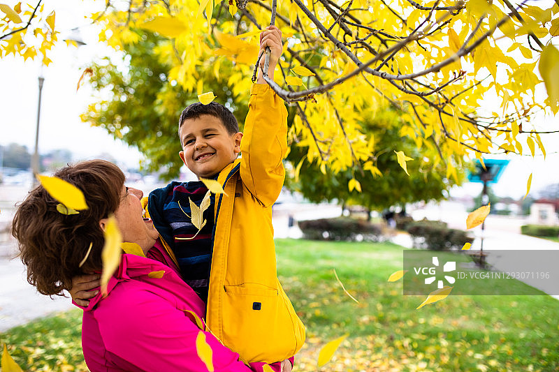 一个可爱的男孩和他的祖母在公园里玩秋天图片素材