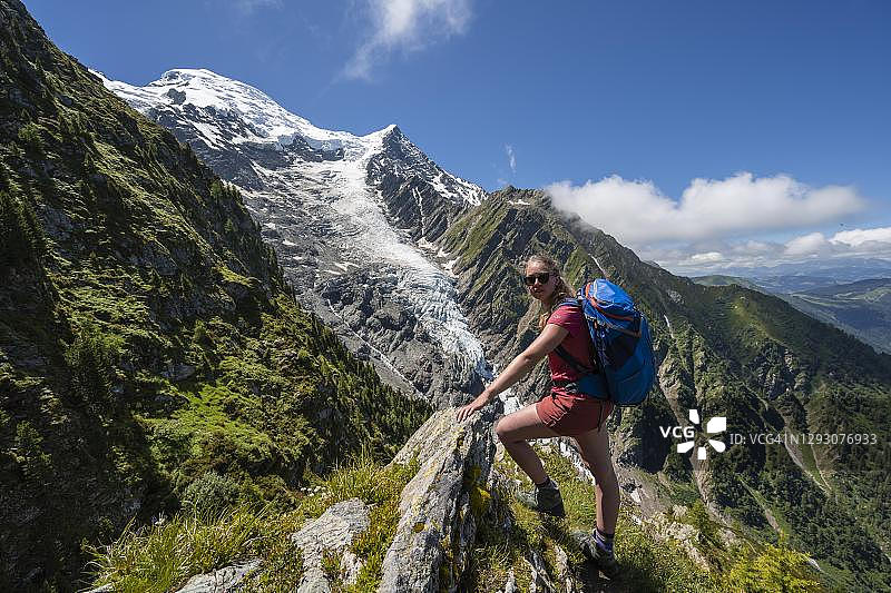 在法国上萨伏伊夏蒙尼的拉乔辛徒步旅行时，一名徒步旅行者正看着相机里的山脉景观，身后是塔纳兹冰川图片素材