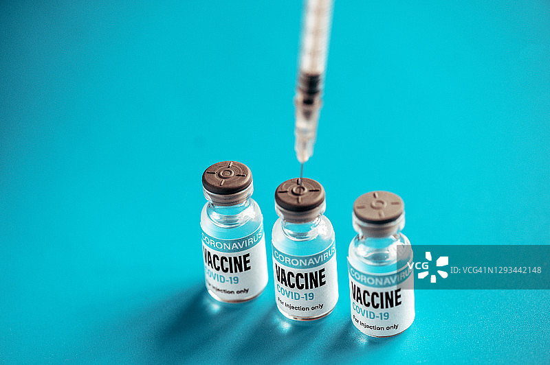 冠状病毒疫苗:绿色背景上的注射器和小瓶图片素材