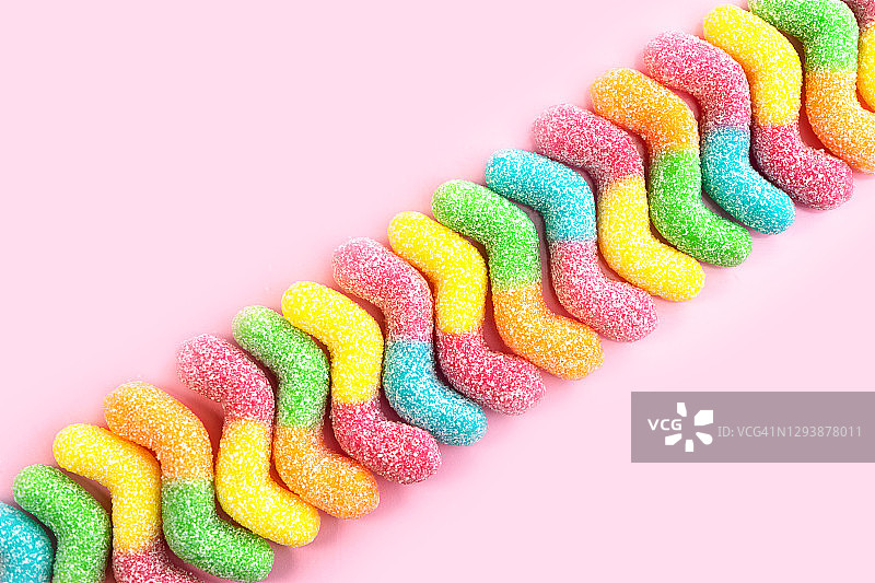Сolored糖果在柔和的粉红色背景。图片素材