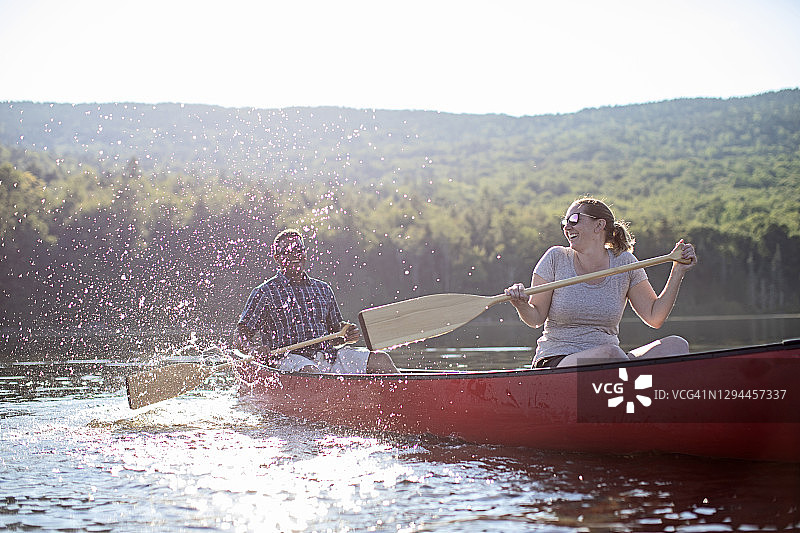 缅因州，一对情侣在独木舟上嬉戏嬉戏，互相泼水嬉戏，开怀大笑图片素材