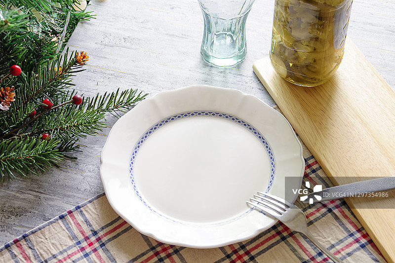 圣诞家庭餐桌设置与空的白色盘子和圣诞木制装饰的桌子上图片素材