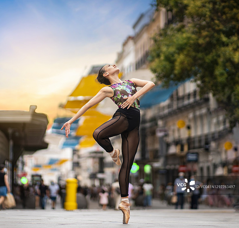 日落时分，一名舞者在城市街道上踮着脚尖练习芭蕾舞图片素材