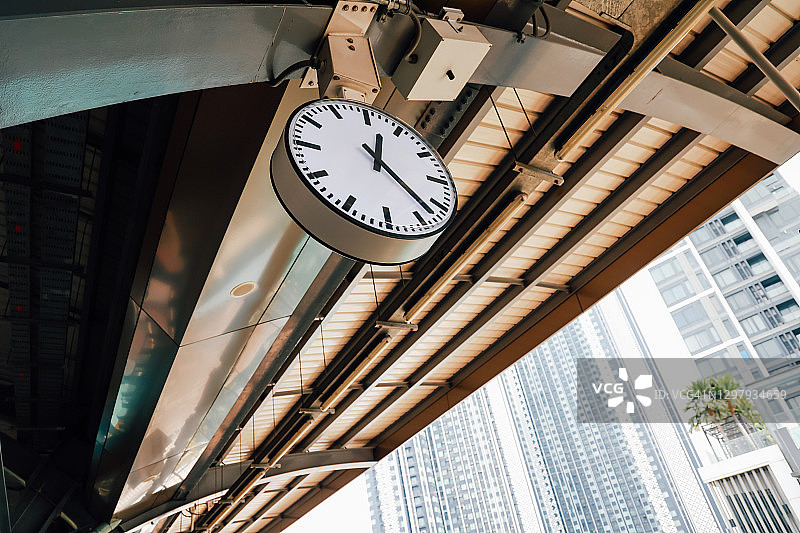 钟挂在市中心的火车站上，在室外有摩天大楼的建筑——准时和时间概念图片素材
