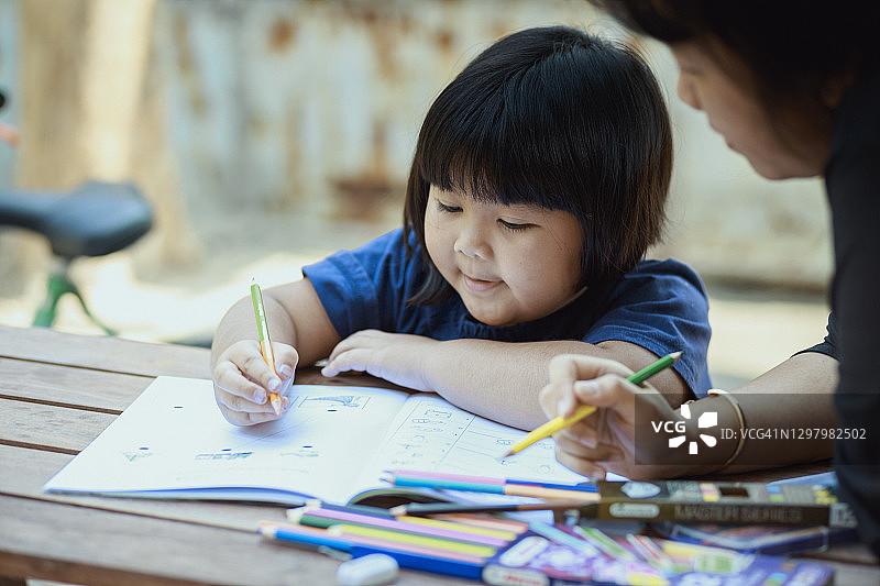 亚洲婴儿女孩和母亲在家里一起学习的时间。社交距离或在家上学的概念。图片素材