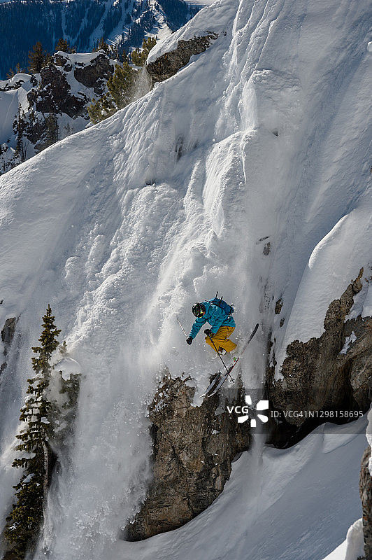 野外滑雪者从山腰的悬崖上跳下图片素材