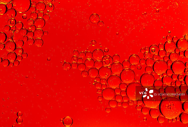 红色艺术的油滴浮在水面上。摘要油泡背景。微距镜头。石油泡沫会消失。图片素材