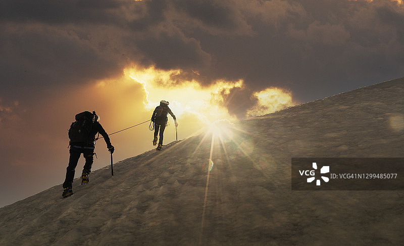 日出时雪坡上的登山者图片素材