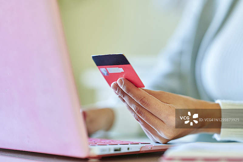一个女人的手用信用卡在网上支付的特写图片素材