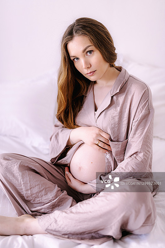 美丽的怀孕年轻欧洲妇女在卧室里的睡衣在家里产假图片素材