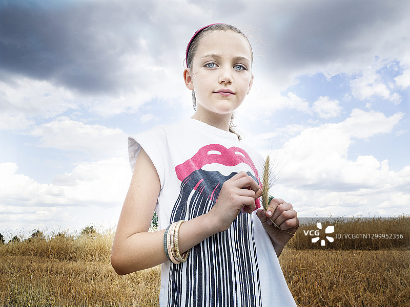 波兰，一个美丽的女孩站在田里，手里拿着一穗小麦图片素材