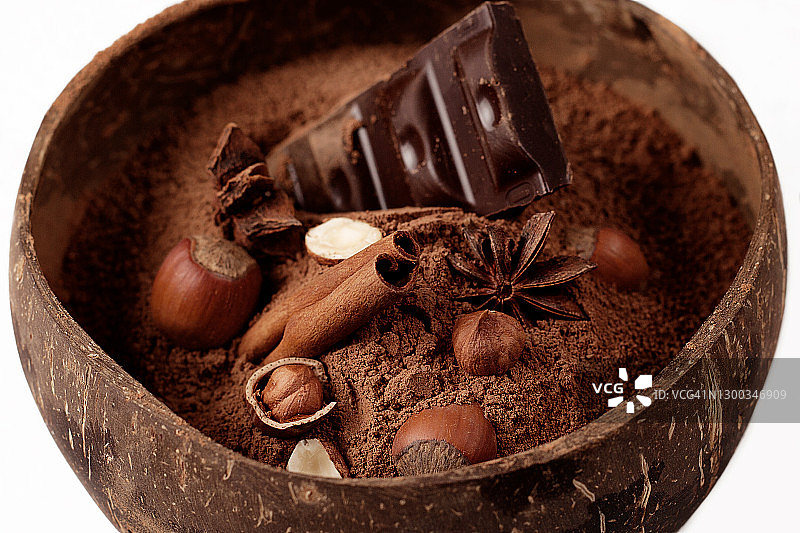 椰子盘里放着黑巧克力、可可粉和榛子图片素材