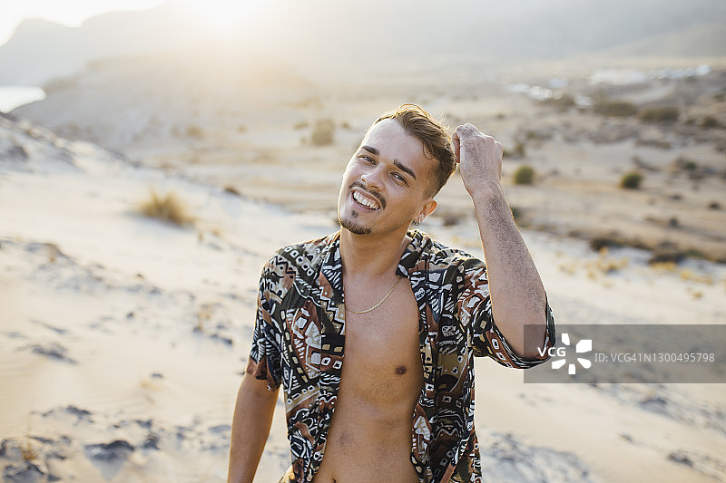 在西班牙塔伯纳斯阿尔梅里亚的沙漠里，快乐英俊的男人穿着敞开的衬衫图片素材