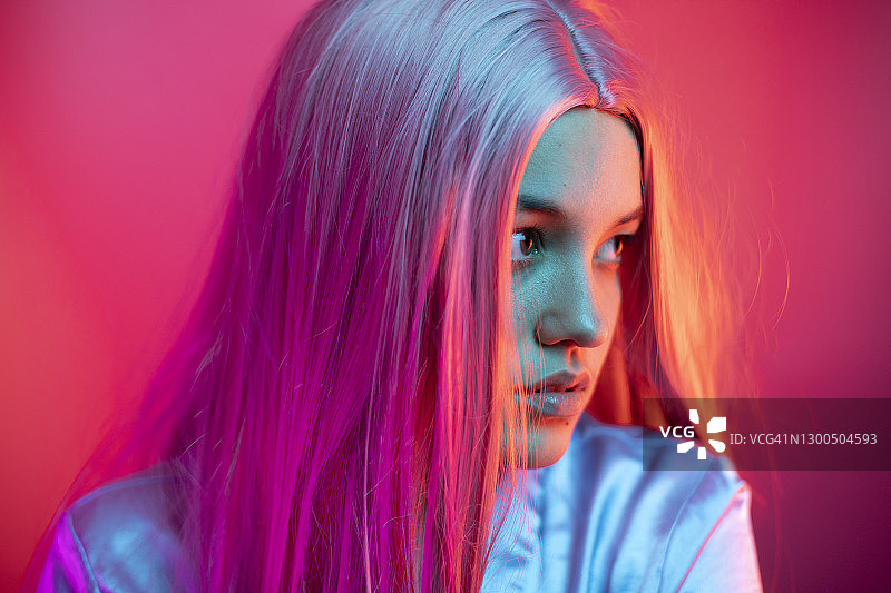 沉思的年轻女人戴着假发的粉红色背景的特写图片素材