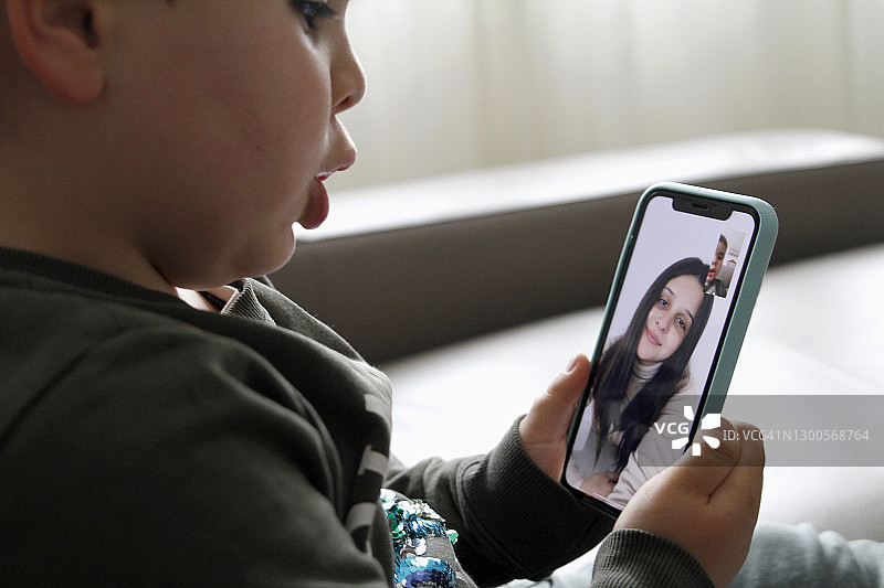 男孩用智能手机和家人视频通话图片素材