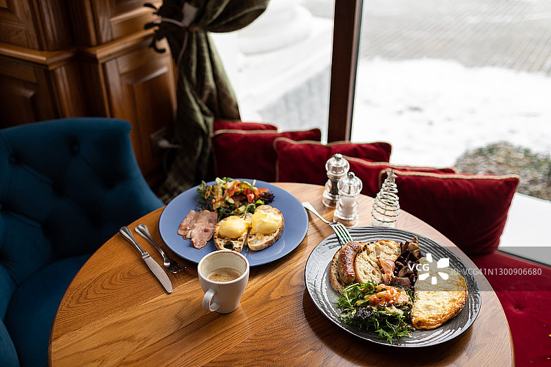 早餐——炒鸡蛋、蔬菜和烤面包，靠在咖啡馆的窗户上。图片素材