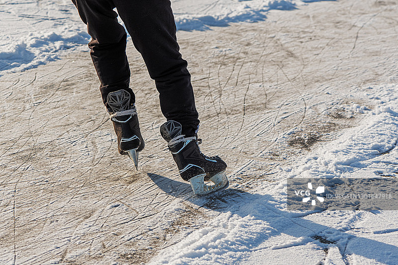 在溜冰场溜冰的人的腿。人们在结冰的湖面上滑冰。后面的观点。冬季休闲活动。图片素材