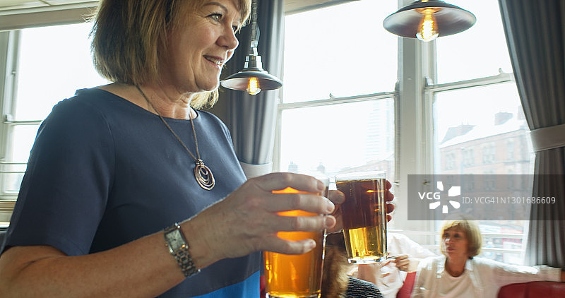 微笑的女人走过酒吧，给自己和朋友带着啤酒图片素材