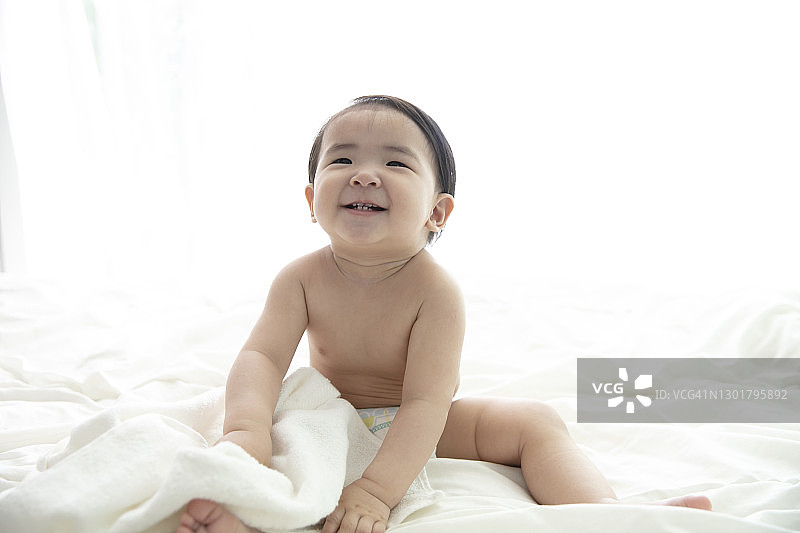 微笑的婴儿坐在床上图片素材