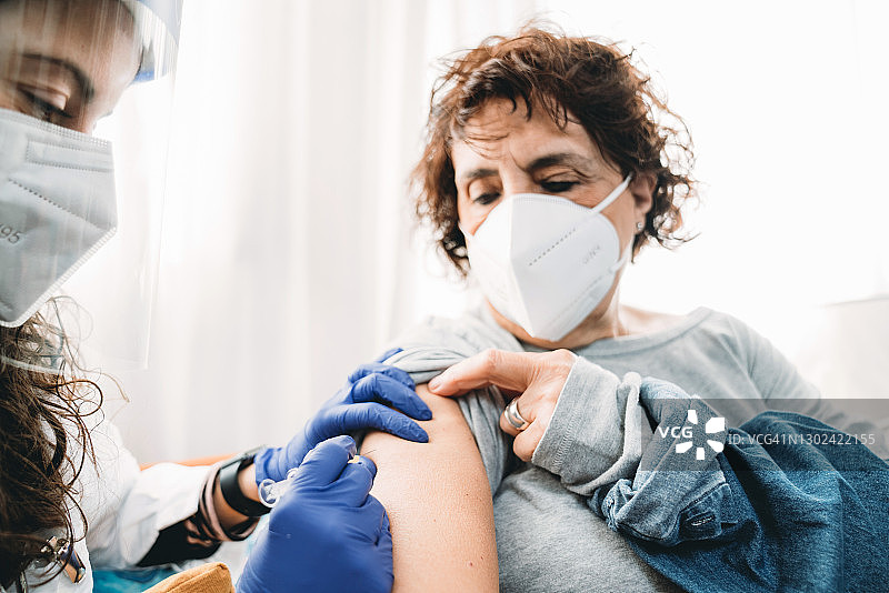 一名女医生正在为一名女士接种Covid-19冠状病毒疫苗图片素材