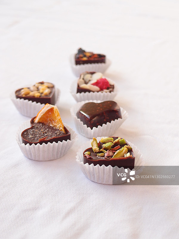 白色桌布上放着美味的自制巧克力、坚果和浆果。巧克力糖果合上图片素材