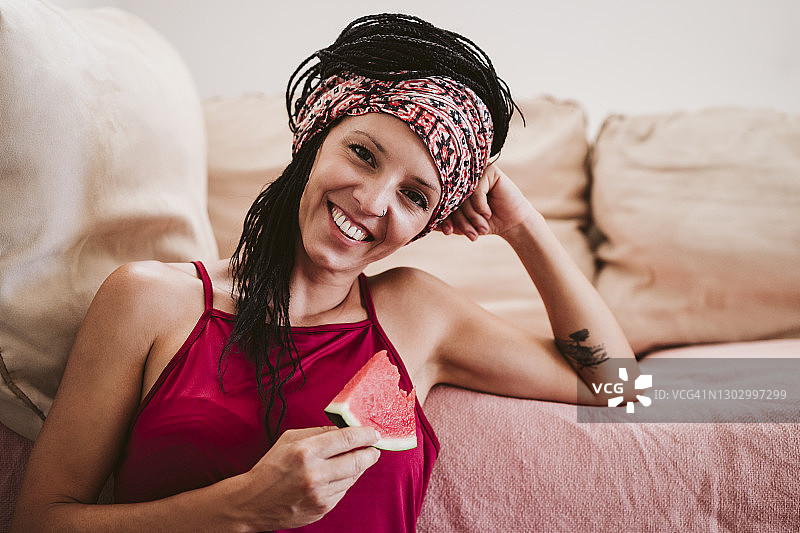 坐在家里吃西瓜的女人微笑着图片素材