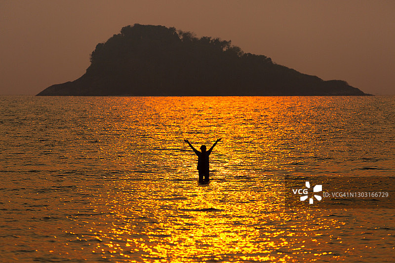 泰国Koh Chang岛的海滩，一个女人的剪影在大海和一个岛屿后面的下午日落前。图片素材