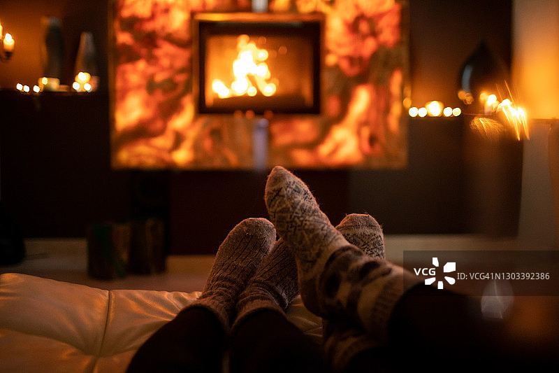 冬天在壁炉旁穿着羊毛袜子的脚。图片素材