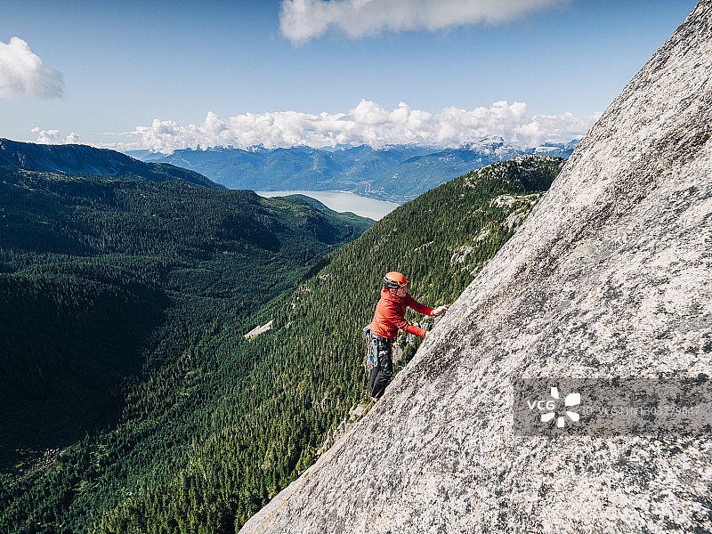 一名攀岩者小心翼翼地爬上山谷上方的一块空白石板图片素材