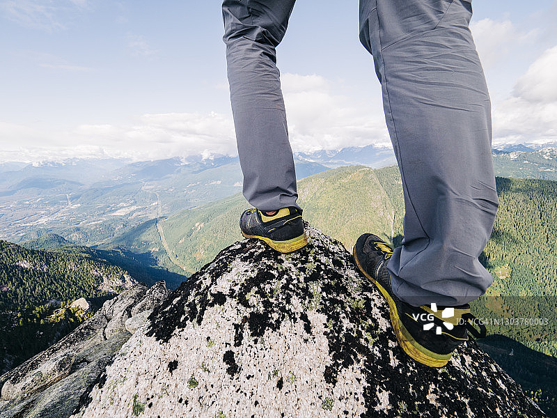 跑步鞋的观点，站在山顶俯瞰一个森林深谷图片素材