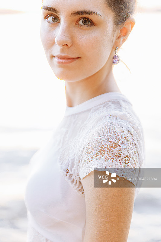柔软的肖像一个年轻美丽的女人穿着白色的裙子。图片素材