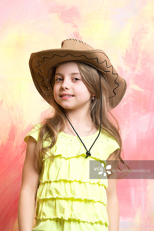 孩子，小女孩微笑着戴着牛仔帽在彩色的背景图片素材