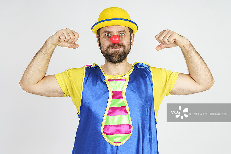 一个穿着亮蓝黄相间衣服的小丑炫耀着他的肌肉图片素材