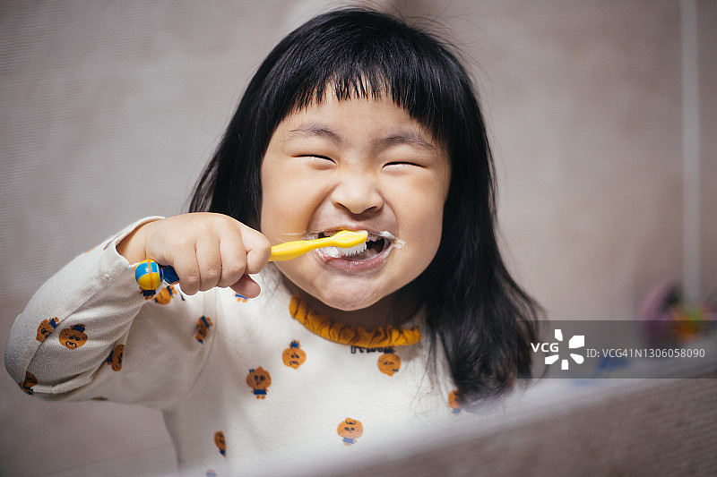 快乐的小女孩在浴室里刷牙图片素材