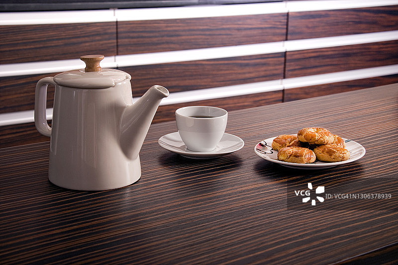 在厨房的木桌上放上一杯咖啡和新鲜的饼干图片素材