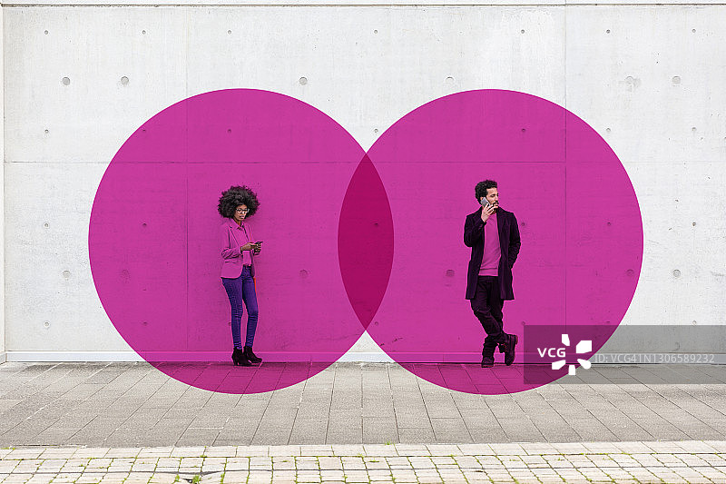 两个重叠的圈视觉社会距离覆盖的男人和女人站在户外，手里拿着智能手机图片素材