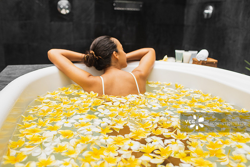 女人享受沐浴在鲜花。浪漫的美容spa。背景模糊和散焦图片素材