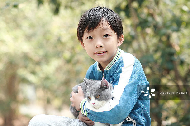 可爱的小男孩依偎着他的小猫。图片素材