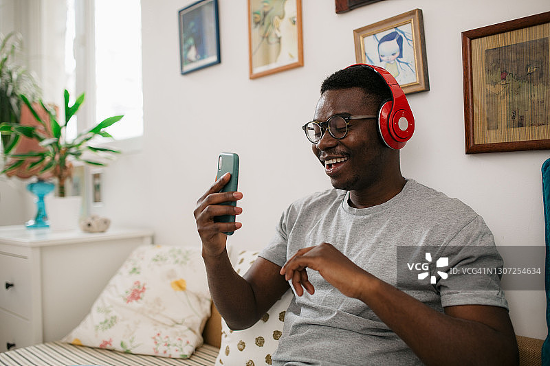 快乐的年轻非裔美国人正在用智能手机听音乐图片素材